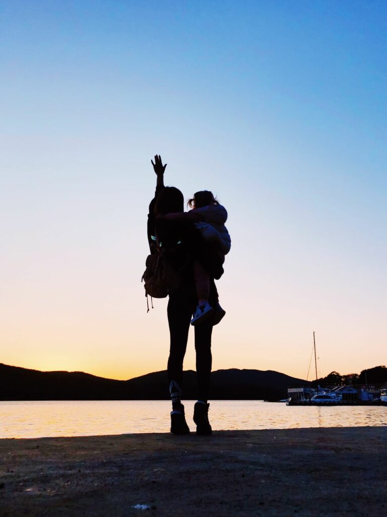 a person carrying a child standing by the harbor